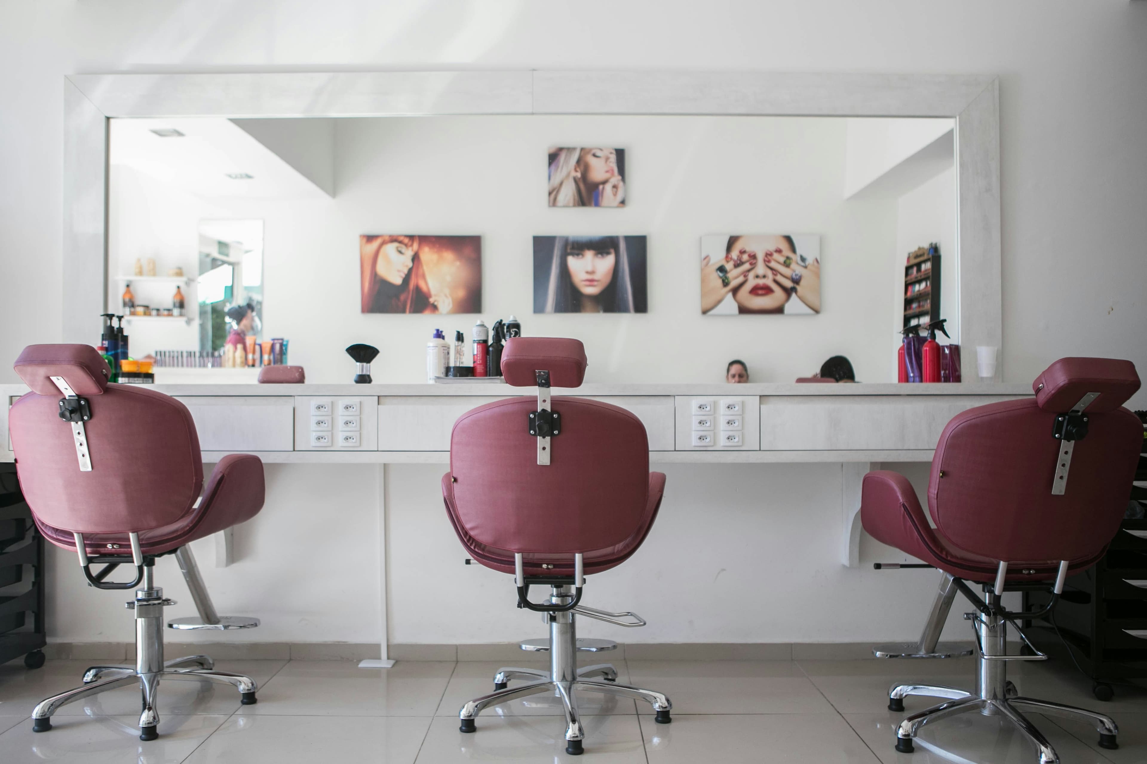Salon de coiffure lumineux — fauteuils alignés et grandes fenêtres